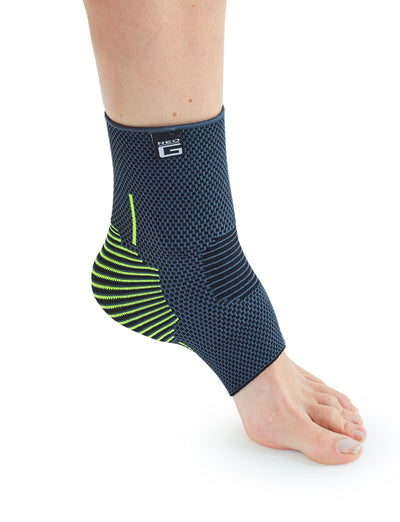 A close-up image of a person's lower leg and foot, wearing a modern, blue and neon yellow ankle brace with structured support. the background is plain white.
