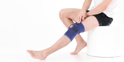 Man sitting down wearing a Neo G Open Knee Support