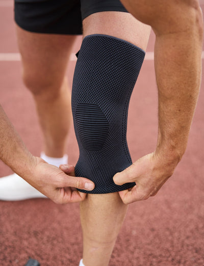 A man on a sports court adjusting his Airflow React Knee Support