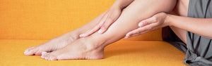 Woman sitting with hands resting on top and bottom of one leg