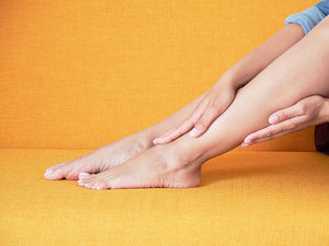 Woman sitting with hands resting on top and bottom of one leg
