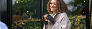 Woman drinking a tea outside whilst wearing arthritis comfort relief gloves for arthritis relief in hands. 