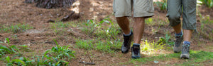 Two people wearing boots, walking in the woods