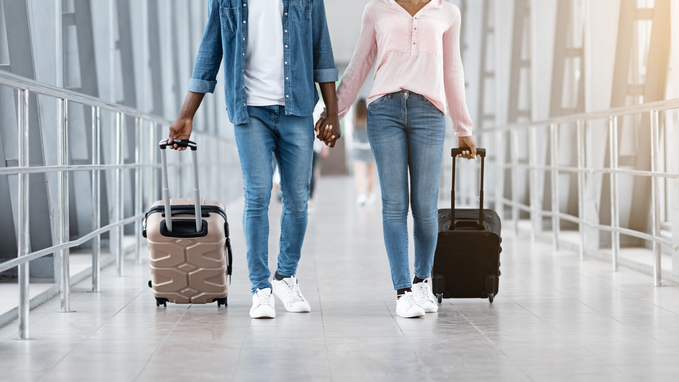 Couple holding hands, walking with luggage cases