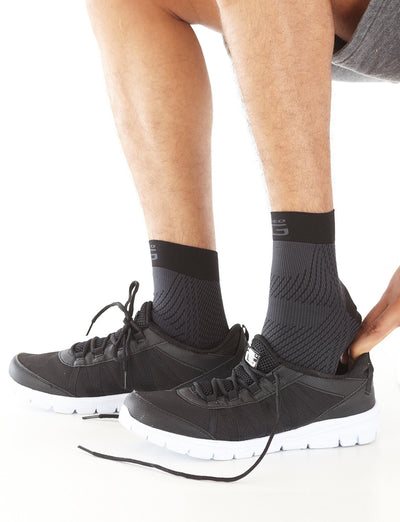 Pair of Feet wearing Neo G Plantar Fasciitis Everyday Support facing side with shoes overtop