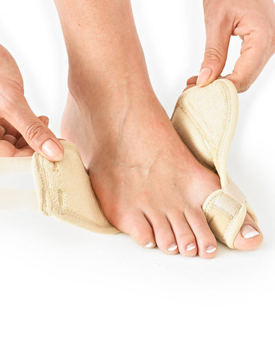 Hands putting Neo G Bunion - Hallux Valgus Soft Support onto right foot highlighting adjustable strap