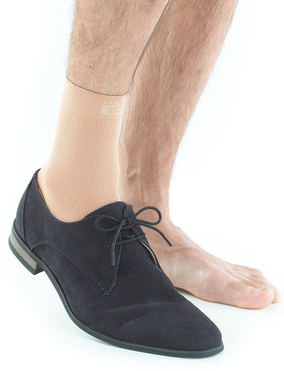 Pair of feet with one wearing beige Neo G Airflow Ankle Support and a suede shoe