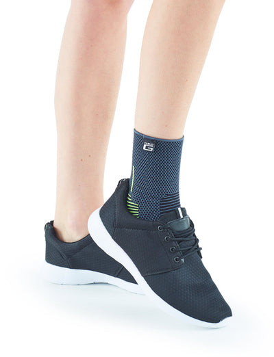 Pair of feet one wearing Neo G Active Ankle Support in sneakers outer view