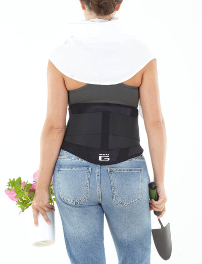 Woman wearing Neo G Back Brace with Power Straps over clothes facing back