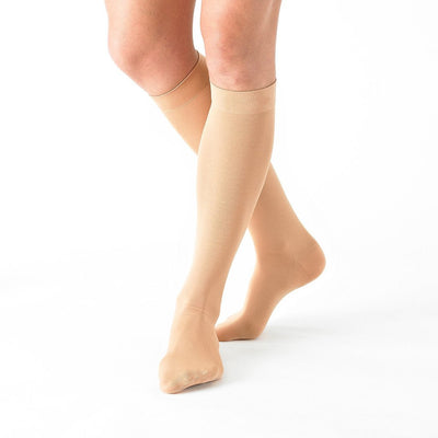 Woman wearing Beige Neo G Energizing Trouser Knee Highs, facing side, showing graduated compression