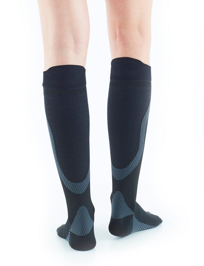 Woman wearing Black Neo G Energizing Active Socks facing back, showing shaped heel cup