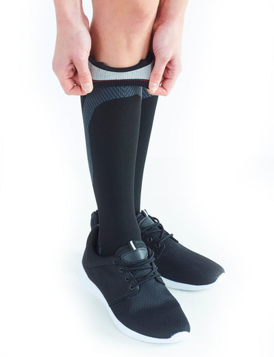 Woman wearing Black Neo G Energizing Active Socks folding down the to  show the silicone top band