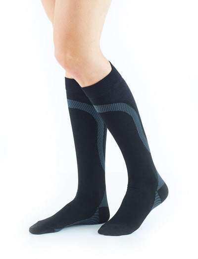 Woman wearing Black Neo G Energizing Active Socks facing side, featuring true graduated compression